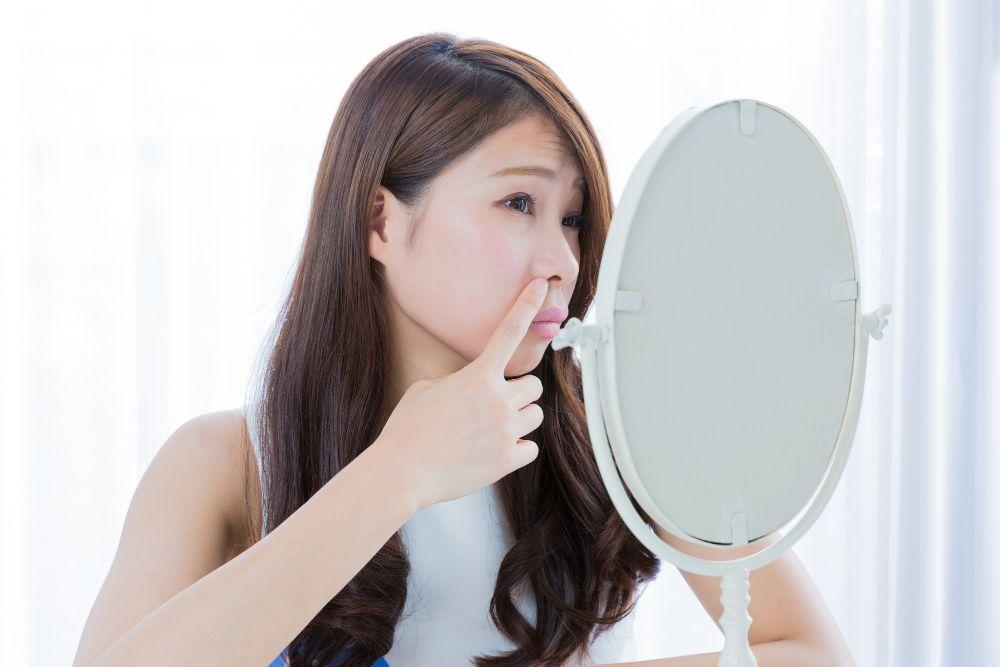 鏡で鼻を気にする女性
