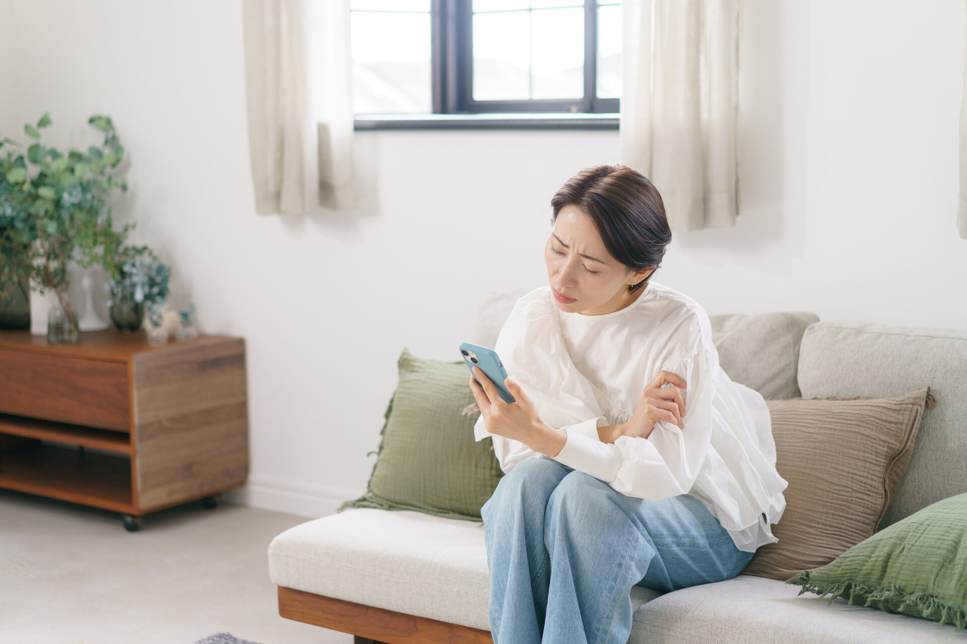 スマートフォンでシミ取り放題について調べる女性